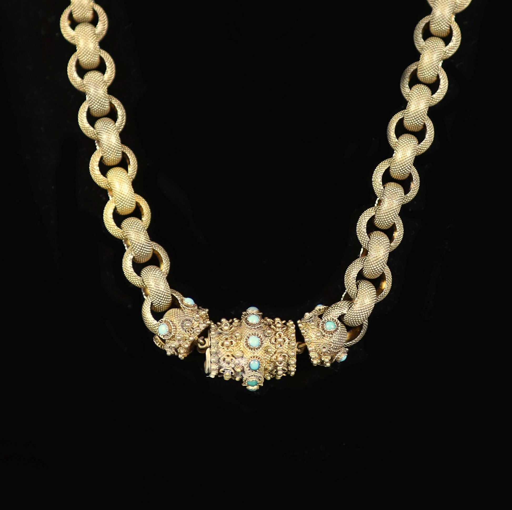 An early 19th century textured gold circular link muff chain, with turquoise set and cannetille work barrel shaped clasp